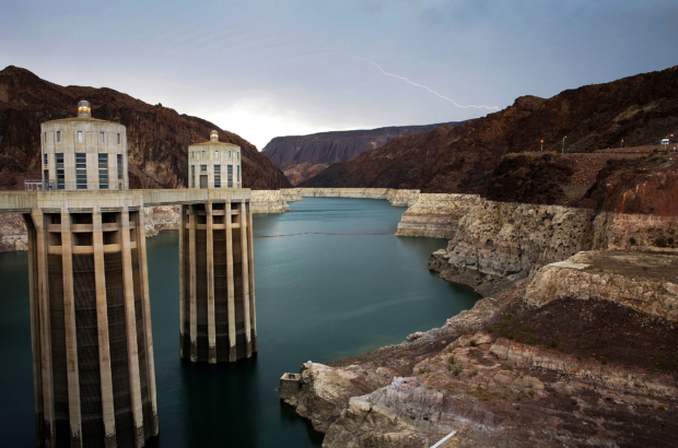 FILE - In this July 28, 2014, file photo, lightning strikes over Lake Mead near Hoover Dam that impounds Colorado River water at the Lake Mead National Recreation Area in Arizona.  The Bureau of Reclamation is forecasting first-ever water shortages because of falling levels at Lake Mead and says the reservoir could drop so low that it might not be able to generate electricity at Hoover Dam. (AP Photo/John Locher, File)